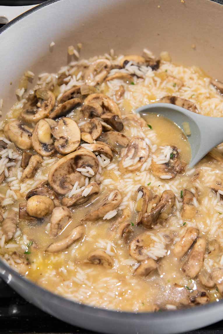 Mushrooms, rice, and broth being cooked.