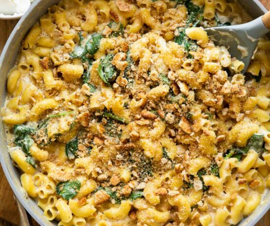 Spinach Ricotta Mac & Cheese being made in a skillet with a spoon.