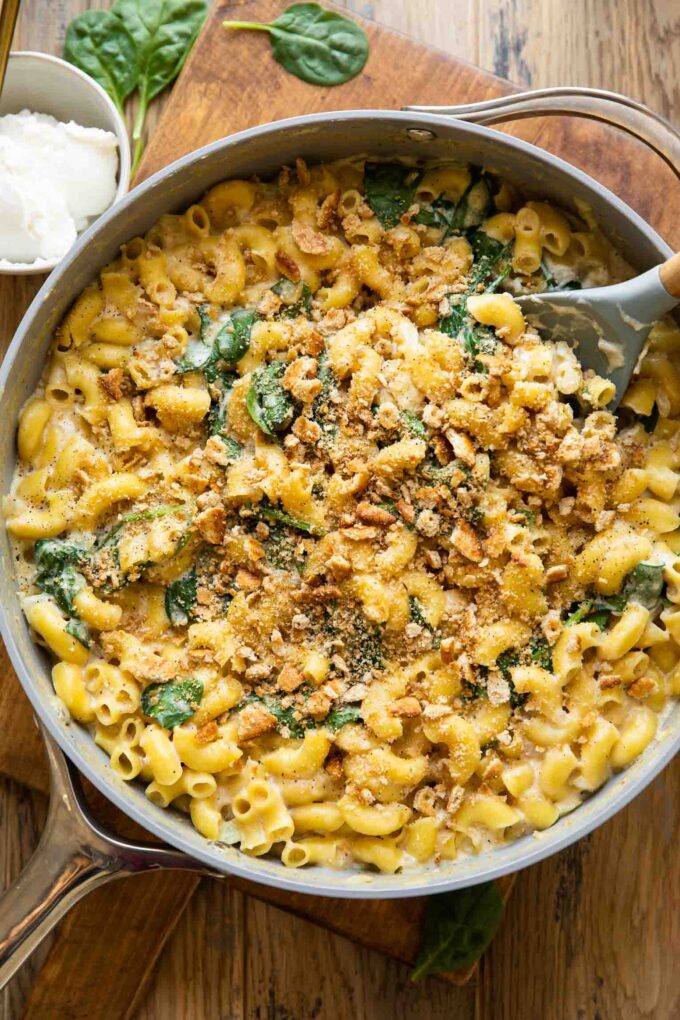 Spinach Ricotta Mac & Cheese being made in a skillet with a spoon.