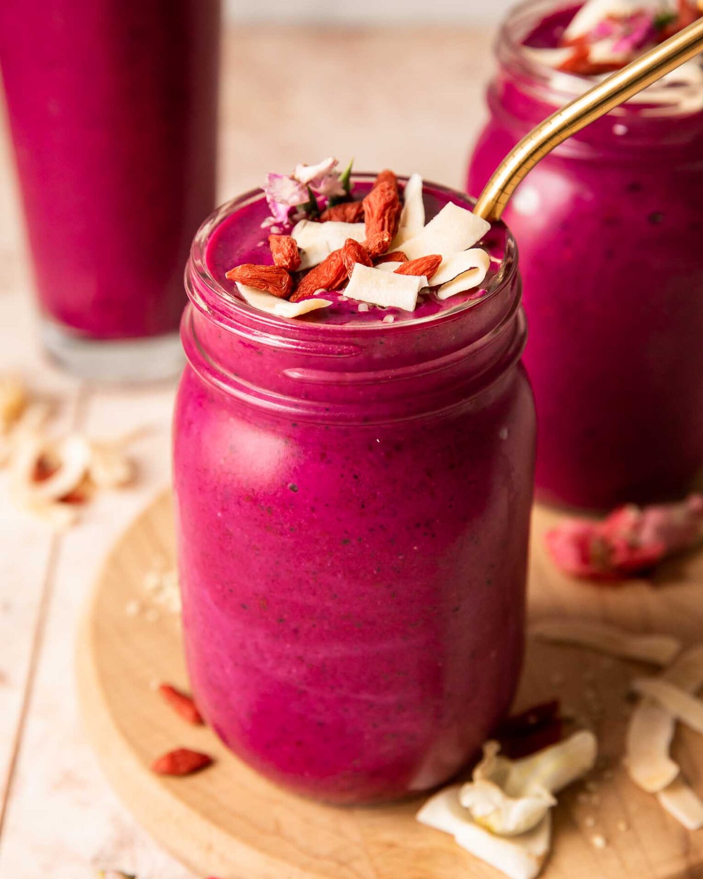 Angled photo of dragon fruit smoothie topped with goji berries, coconut, and hemp seeds.
