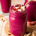 Angled photo of dragon fruit smoothie topped with goji berries, coconut, and hemp seeds.