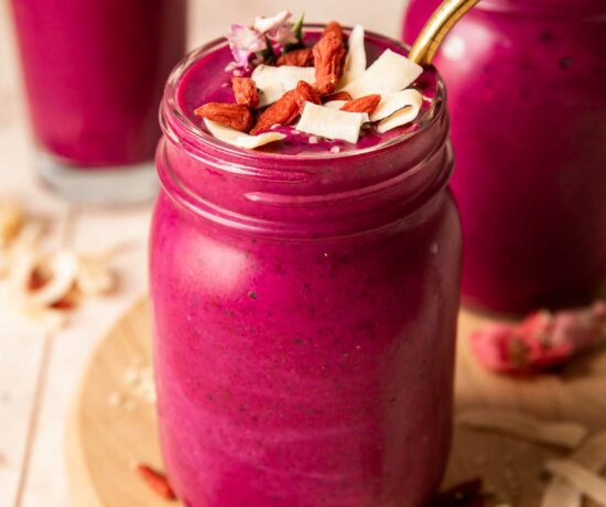 Angled photo of dragon fruit smoothie topped with goji berries, coconut, and hemp seeds.