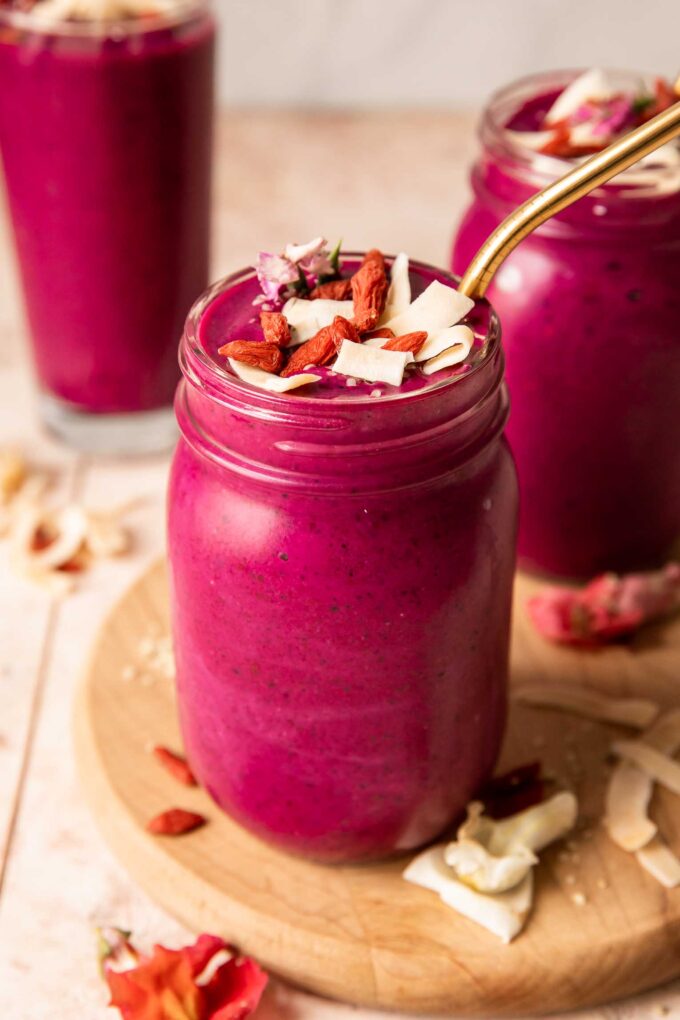Angled photo of dragon fruit smoothie topped with goji berries, coconut, and hemp seeds.