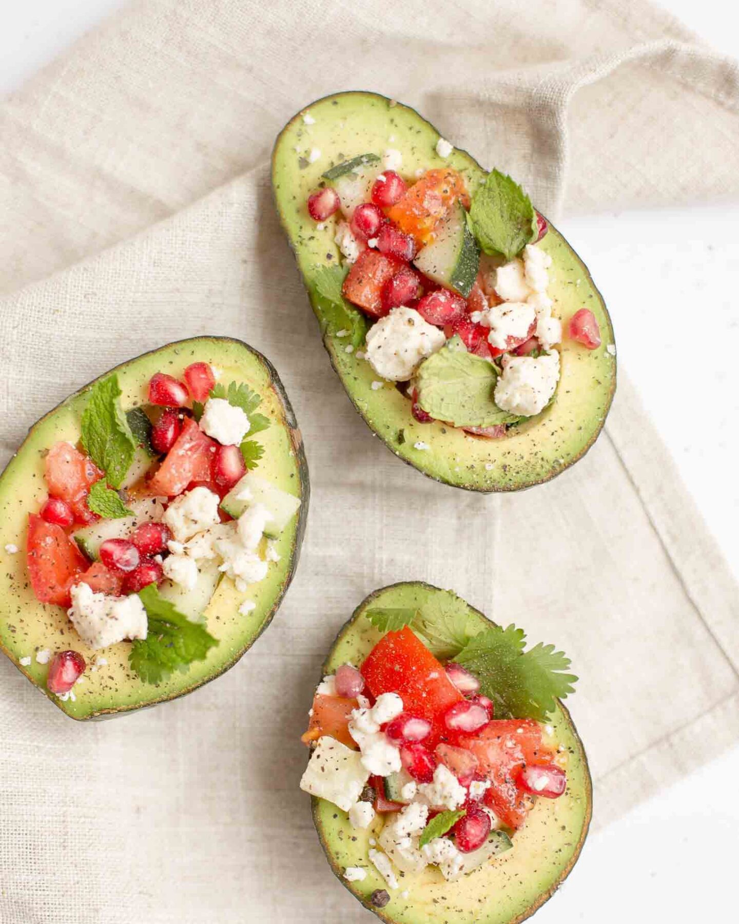 Avocados topped with vegetables and feta cheese.