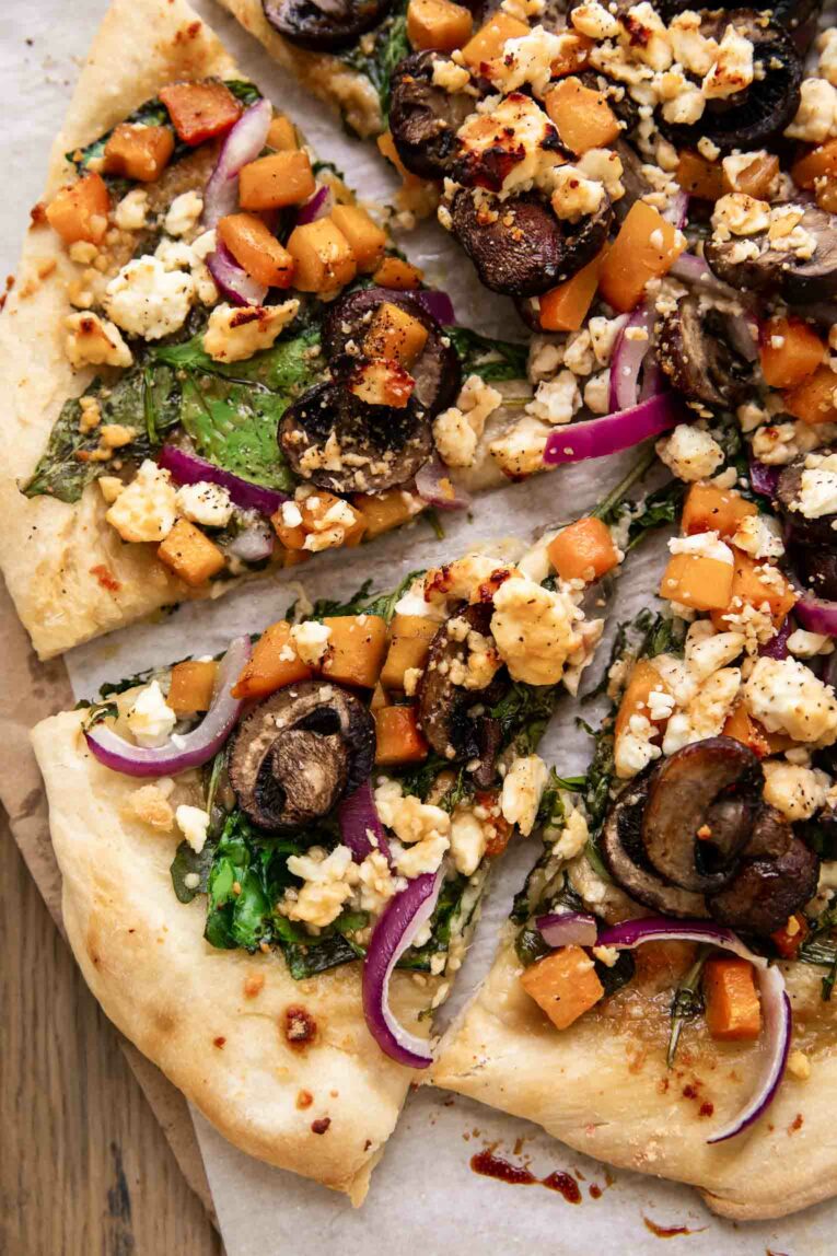 Sliced hot honey pizza with mushrooms, feta, onions, and arugula.