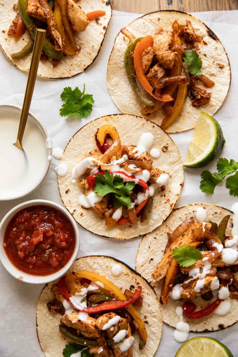 Top photo of chicken fajita tacos, salsa, cream sauce, and cilantro.