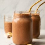 Chocolate banana smoothie recipe in a mason jar with a straw.