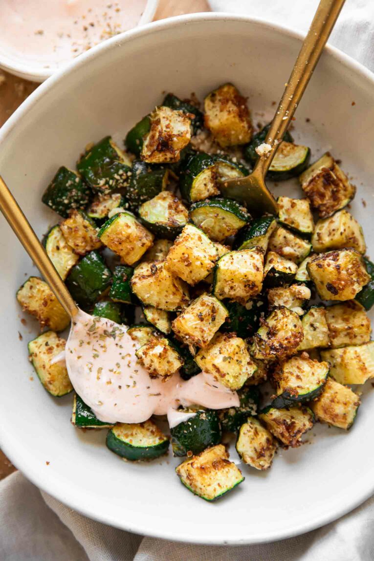 Crispy Air Fryer Zucchini in a bowl with yogurt sriracha sauce.