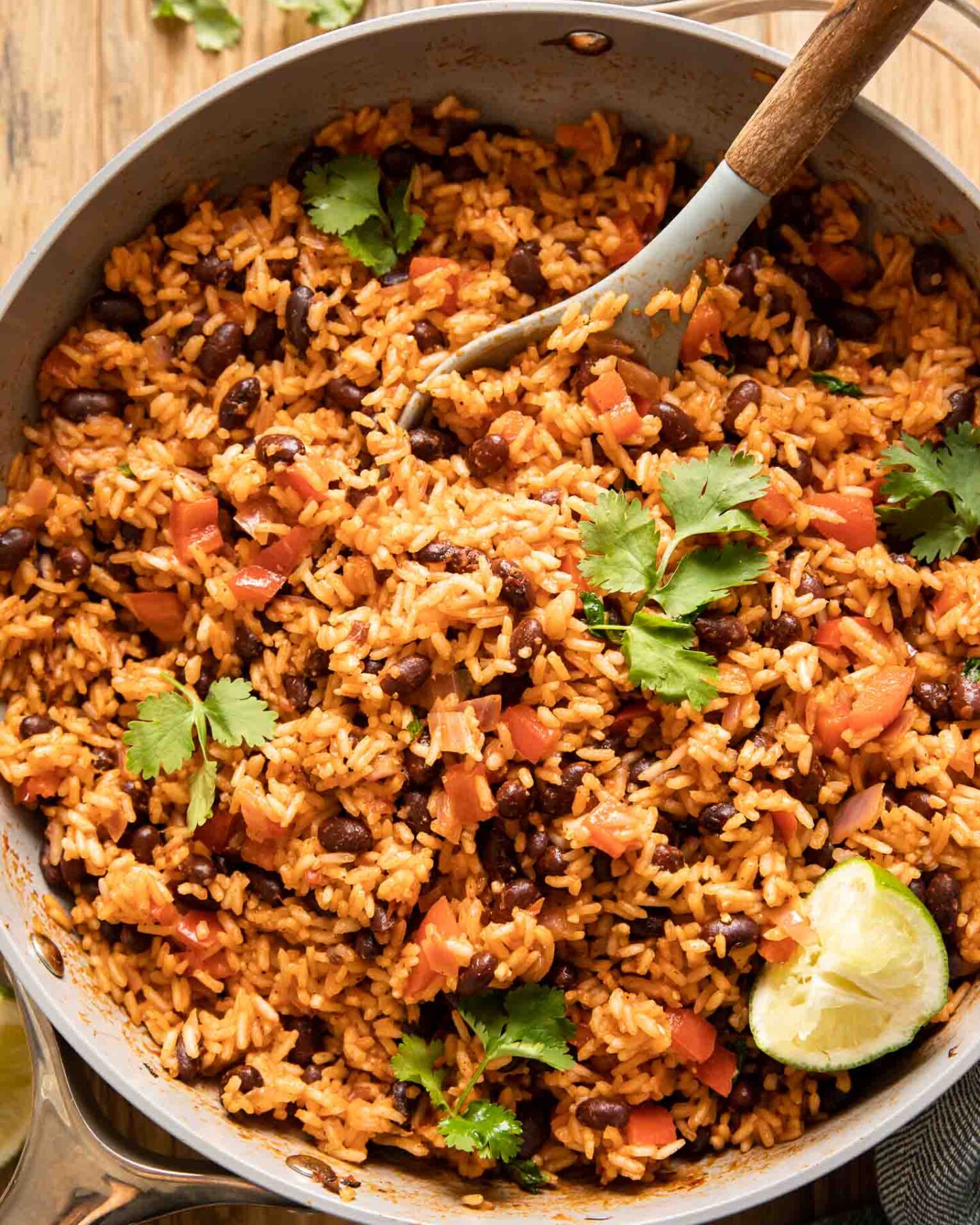Spanish rice and red beans in a pan with cilantro and lime.
