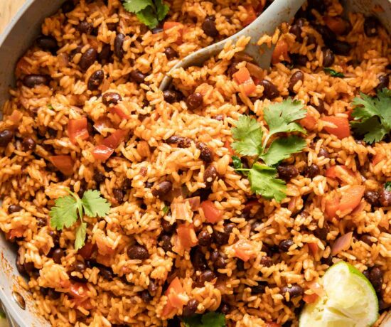 Spanish rice and red beans in a pan with cilantro and lime.