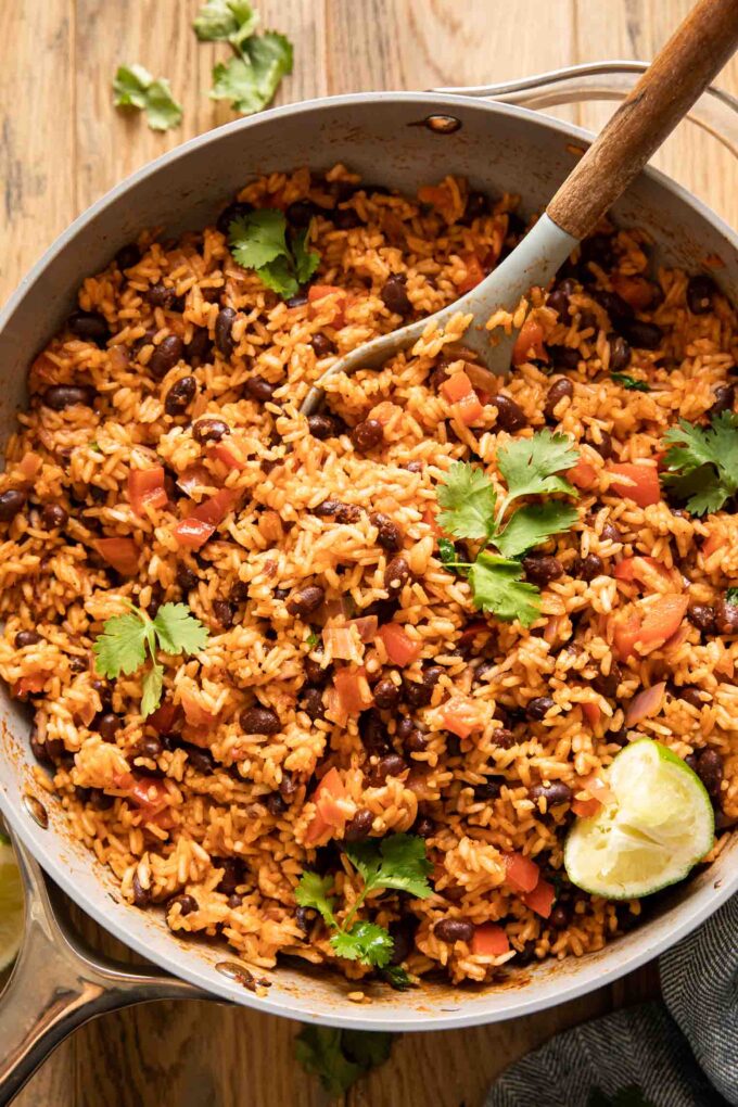 Spanish rice and red beans in a pan with cilantro and lime.