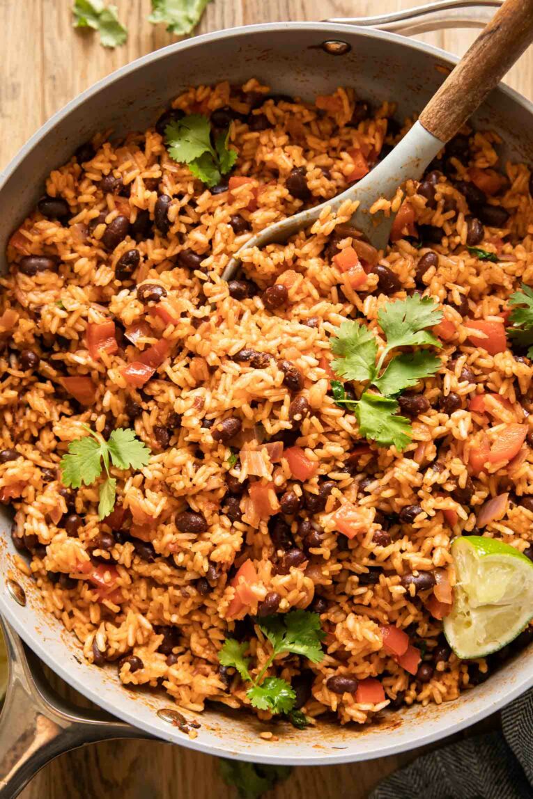 Close up of Spanish Rice & Beans in a large pan with a spoon.