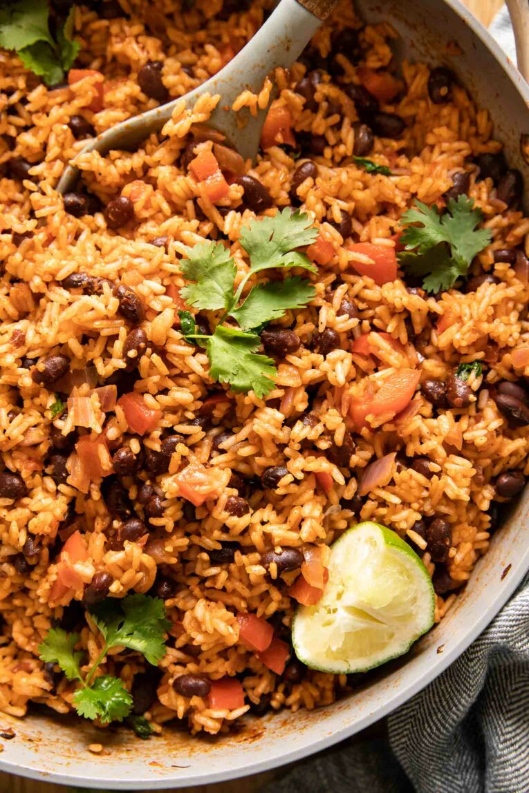 Close up of Spanish rice, red beans, cilantro, bell peppers, and lime.
