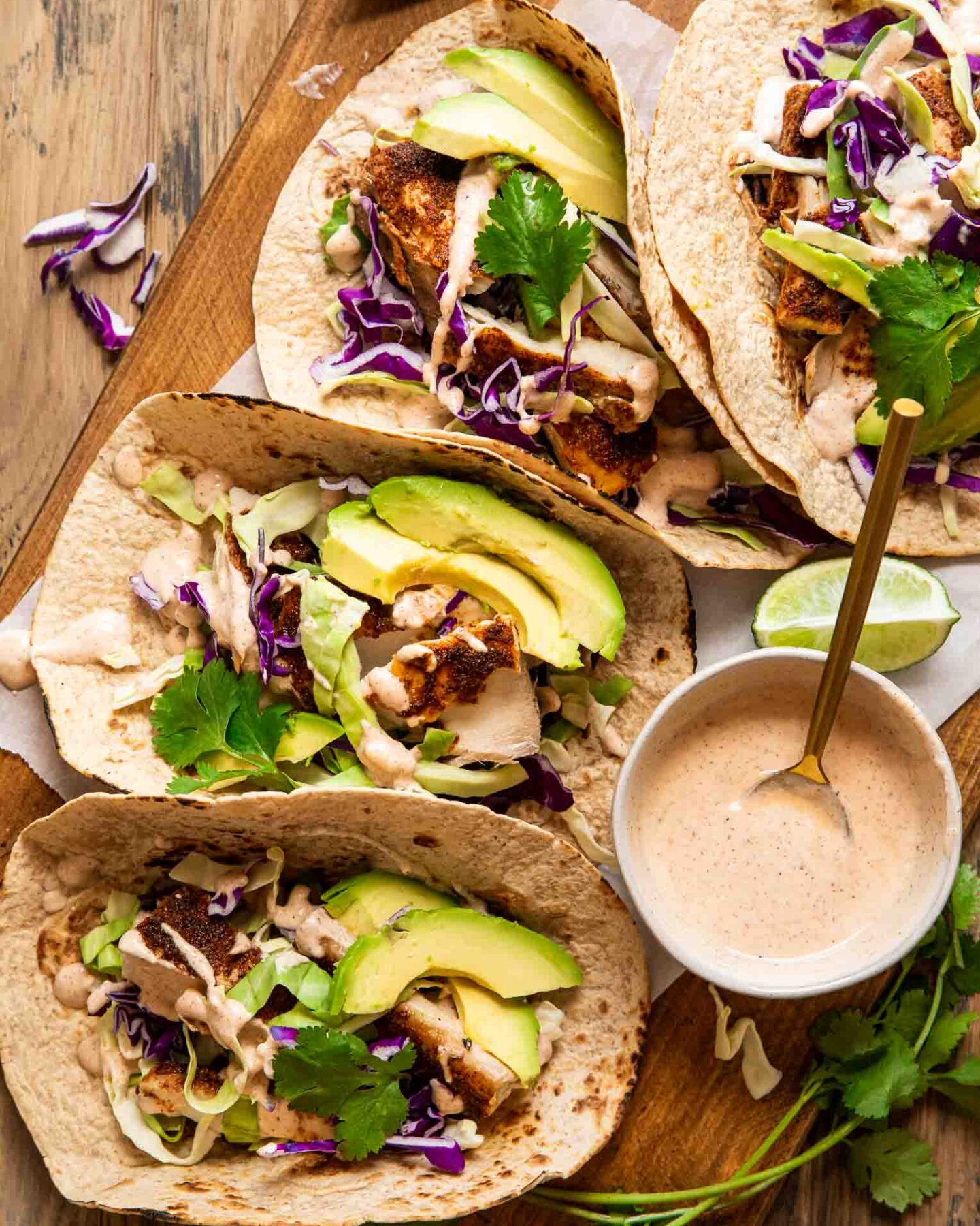 Baked mahi-mahi tacos with a cream sauce, cabbage, and avocado.