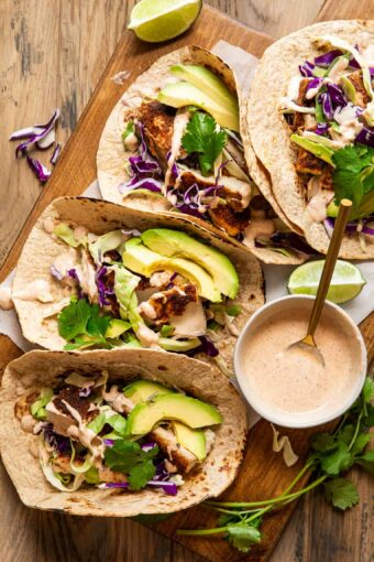 Baked mahi-mahi tacos with a cream sauce, cabbage, and avocado.