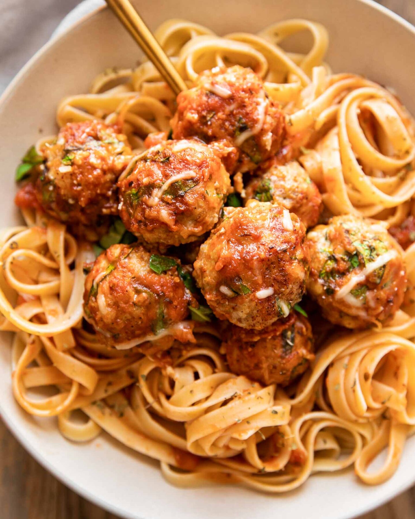 Baked Spinach Chicken Meatballs in a dish with fettuccine.