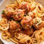 Baked Spinach Chicken Meatballs in a dish with fettuccine.
