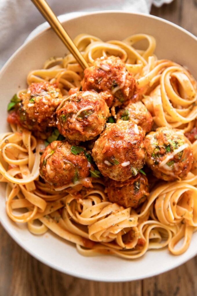 Baked Spinach Chicken Meatballs in a dish with fettuccine.