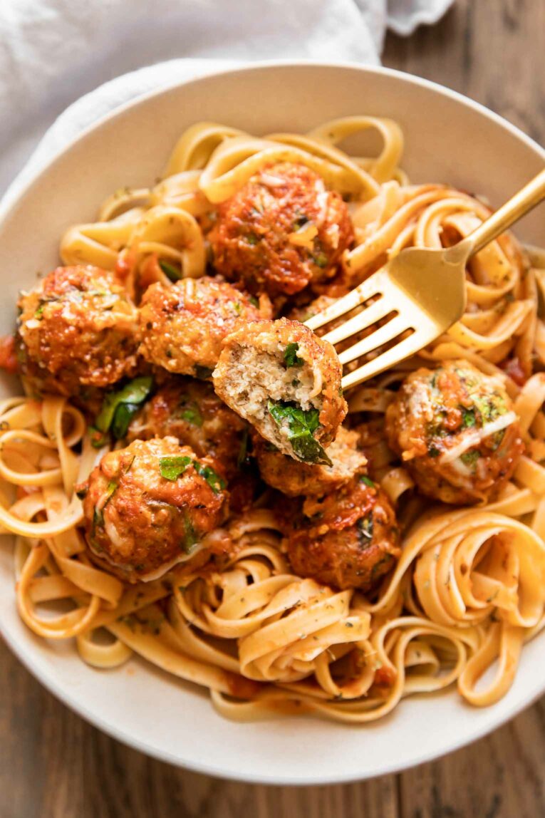 Baked chicken meatballs with fettuccine, spinach, parmesan, and pasta sauce.