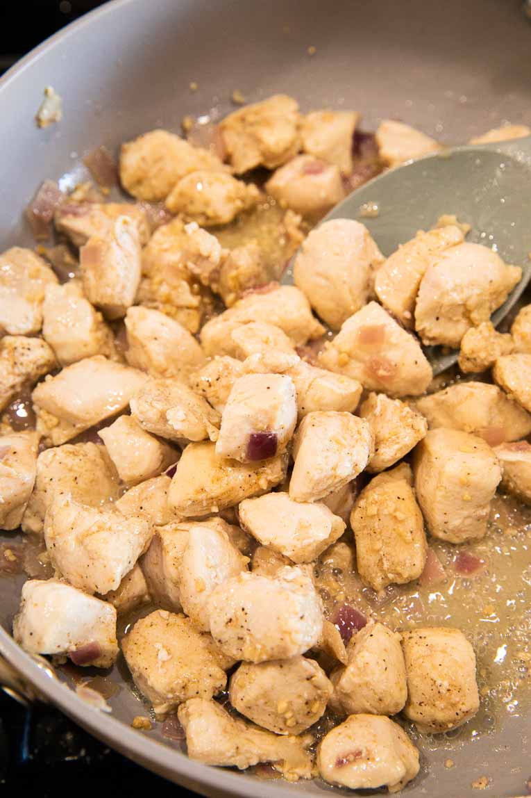 Cubed chicken being cooked in a non stick pan.