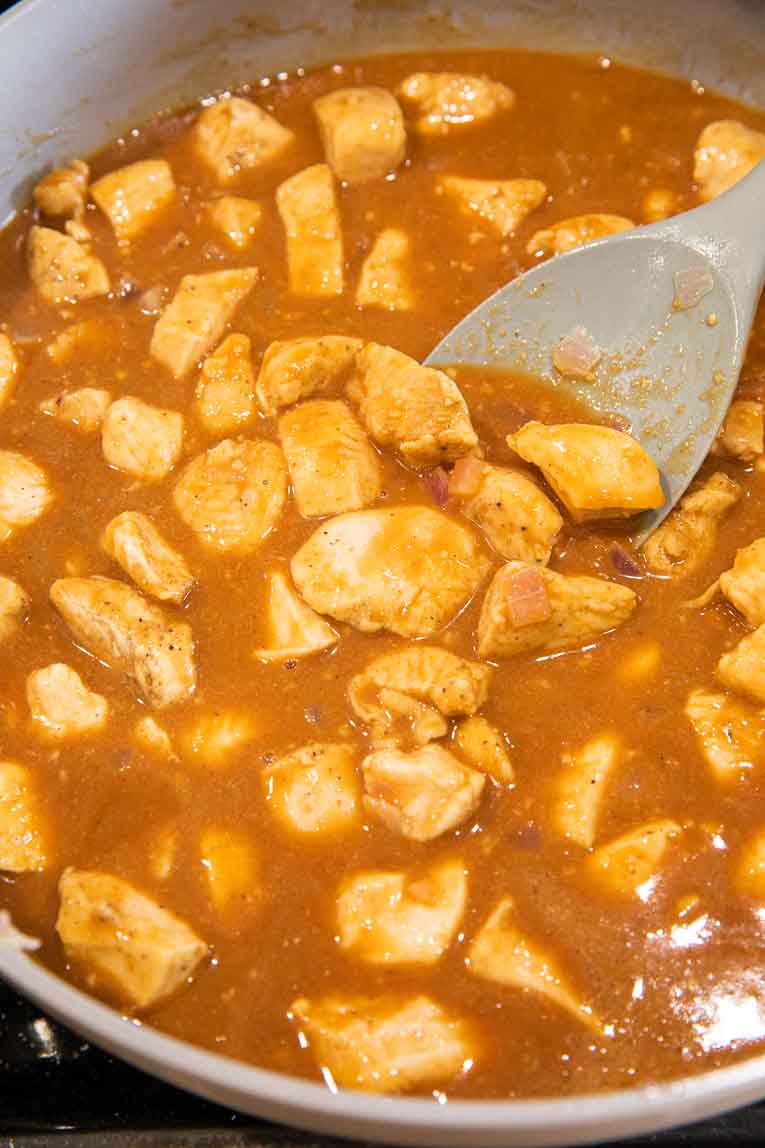 Peanut butter sauce with chicken being cooked in a pan.