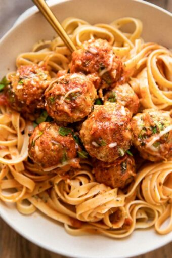 Baked Spinach Chicken Meatballs in a dish with fettuccine.