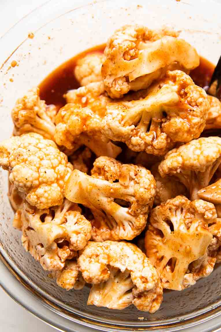 Close up of cauliflower being soaked in buffalo sauce.