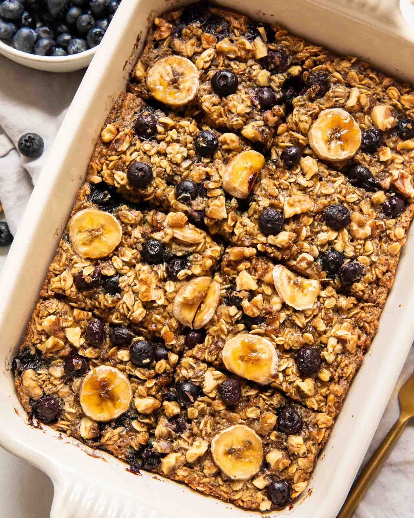 Blueberry banana baked oatmeal in a casserole dish topped with fresh fruit.