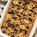 Blueberry banana baked oatmeal in a casserole dish topped with fresh fruit.