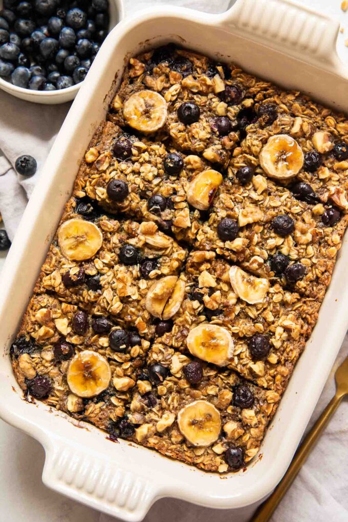 Blueberry banana baked oatmeal in a casserole dish topped with fresh fruit.