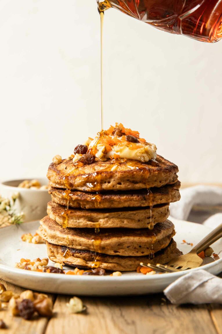 Syrup being poured over carrot cake pancakes.