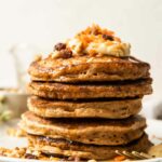 Walnuts and raisins on a stack of carrot cake pancakes.