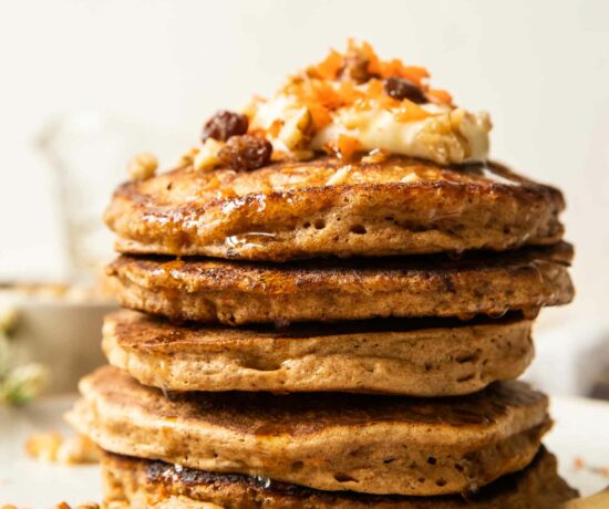 Walnuts and raisins on a stack of carrot cake pancakes.
