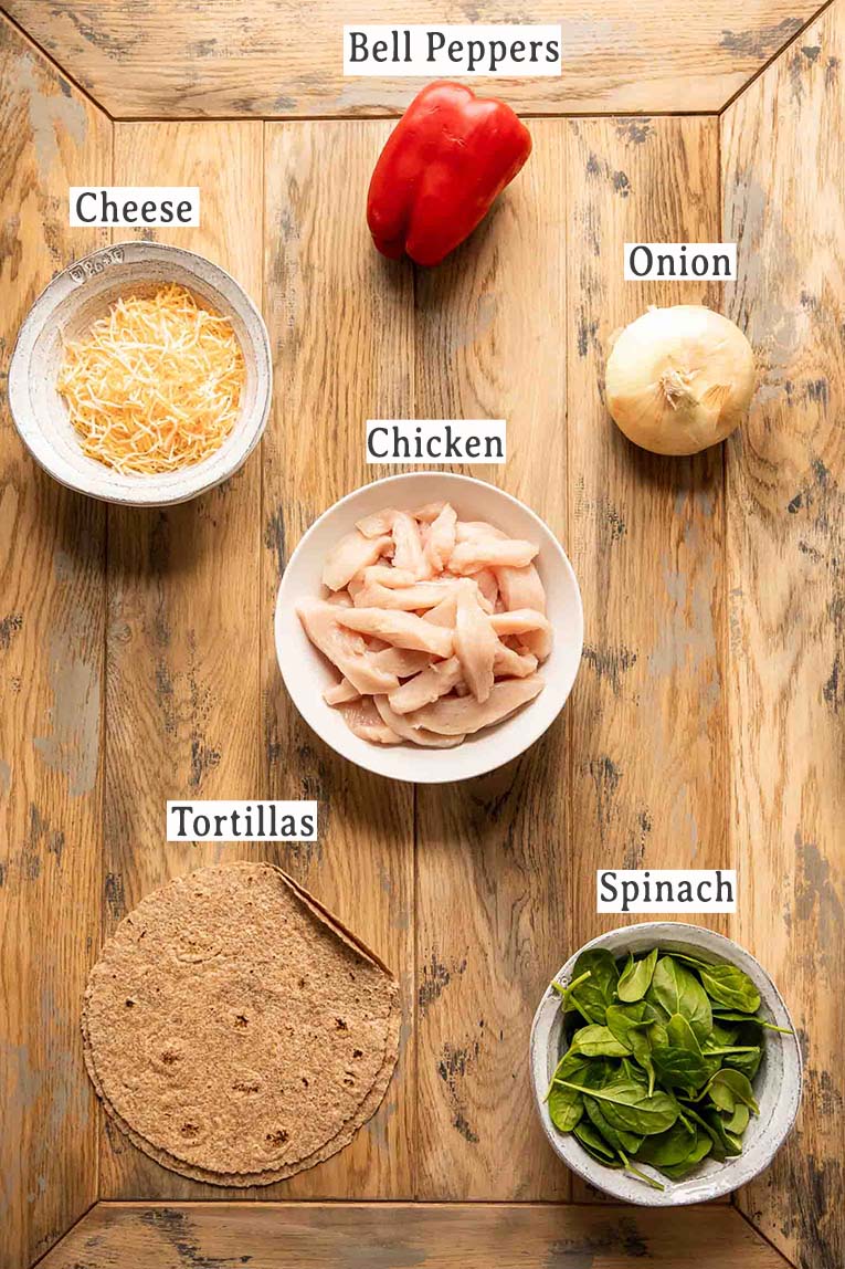 Chicken, peppers, cheese, tortillas, onion, and spinach for a fajita casserole.