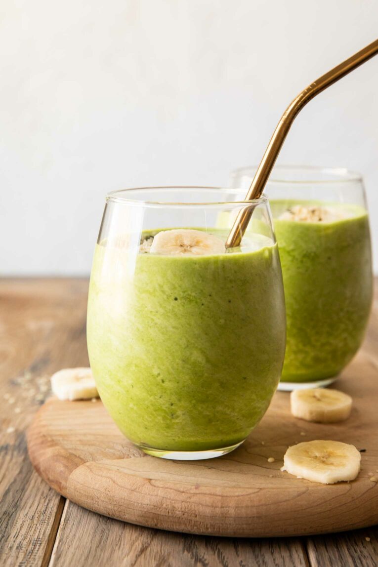 Spinach banana smoothie recipe in glasses with straws.