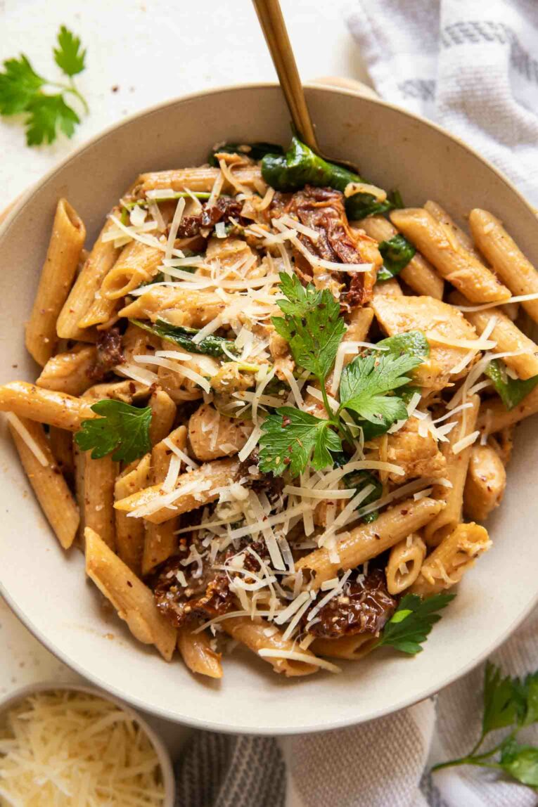 Sun dried tomato chicken pasta with parsley and spinach.