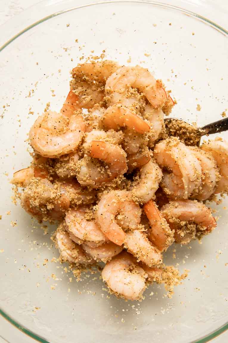 Shrimp in a mixing bowl with flour and seasoning.