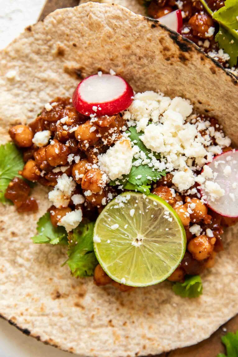 Vegan taco with chickpeas, vegan cheese, radishes, cilantro, and lime.