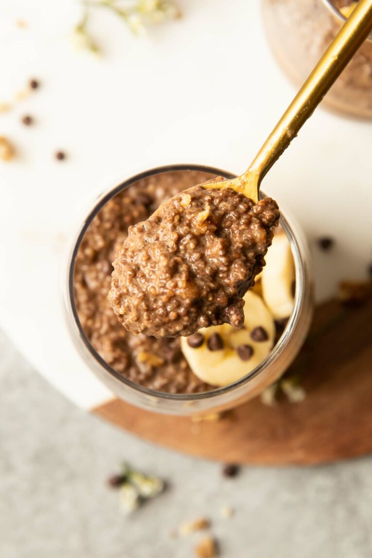 Spoon scooping out chocolate banana chia pudding from a jar.