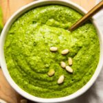 Kale pesto that's creamy and delicious in a bowl with a spoon.