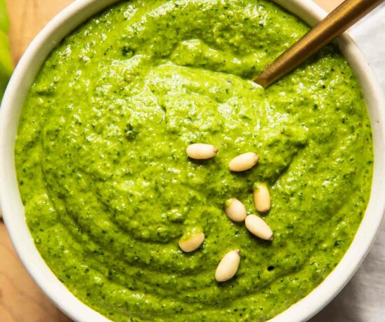 Kale pesto that's creamy and delicious in a bowl with a spoon.