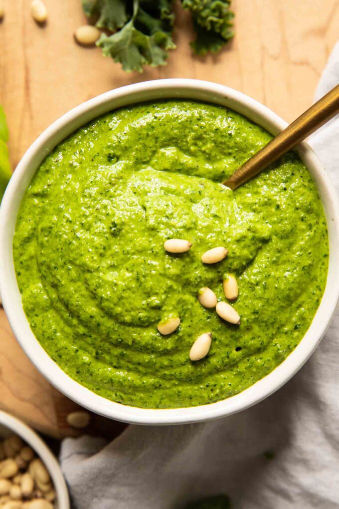 Kale pesto that's creamy and delicious in a bowl with a spoon.
