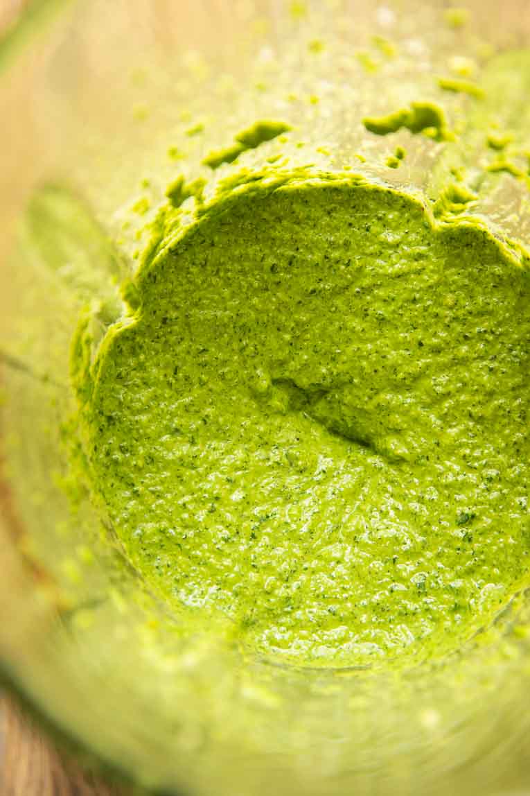Kale, basil, garlic, and pesto ingredients blended in a food processor.