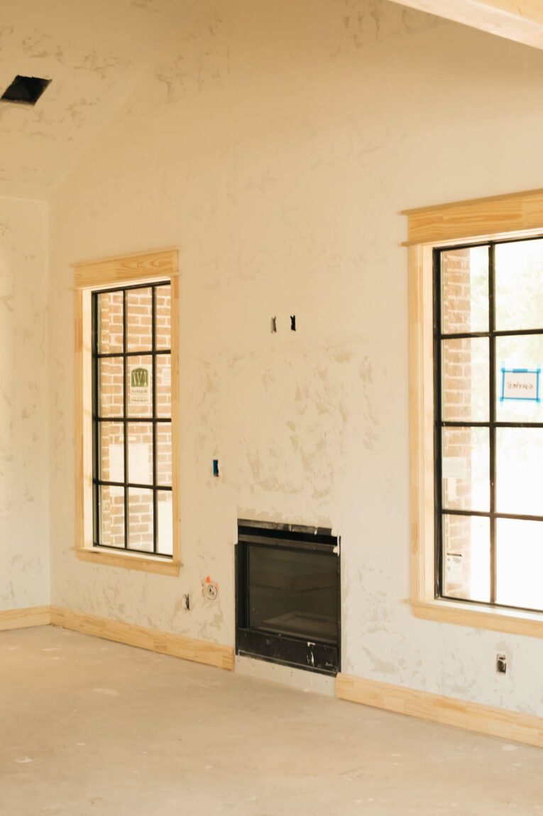 Living room unfinished fireplace with black grid windows.