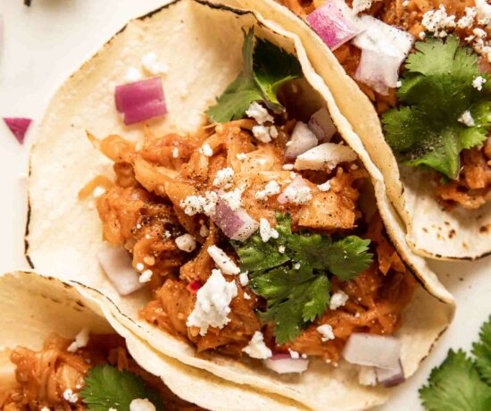 Close up of jackfruit pulled pork tacos with cilantro, cotija cheese, and onions.