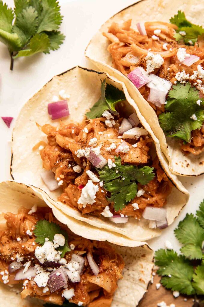 Close up of jackfruit pulled pork tacos with cilantro, cotija cheese, and onions.