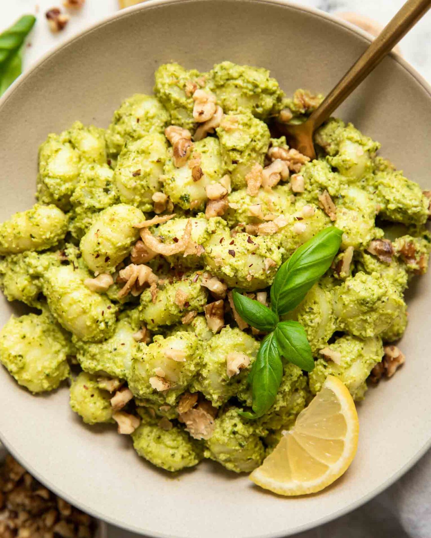 Pesto Gnocchi in a bowl with lemon, kale, and basil.
