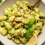 Pesto Gnocchi in a bowl with lemon, kale, and basil.