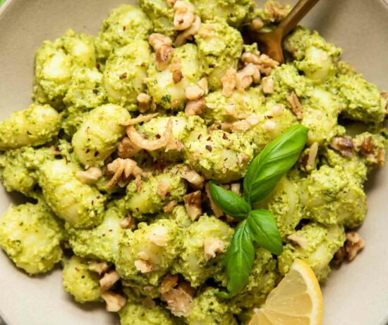 Pesto Gnocchi in a bowl with lemon, kale, and basil.