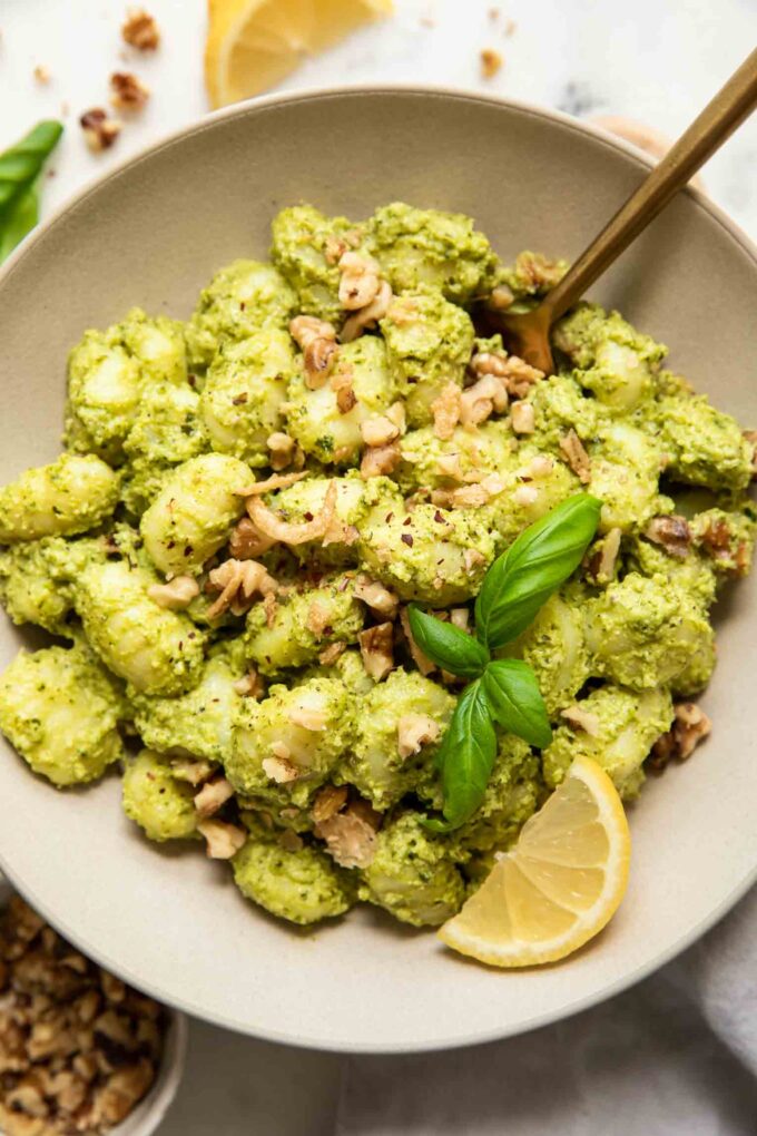 Pesto Gnocchi in a bowl with lemon, kale, and basil.